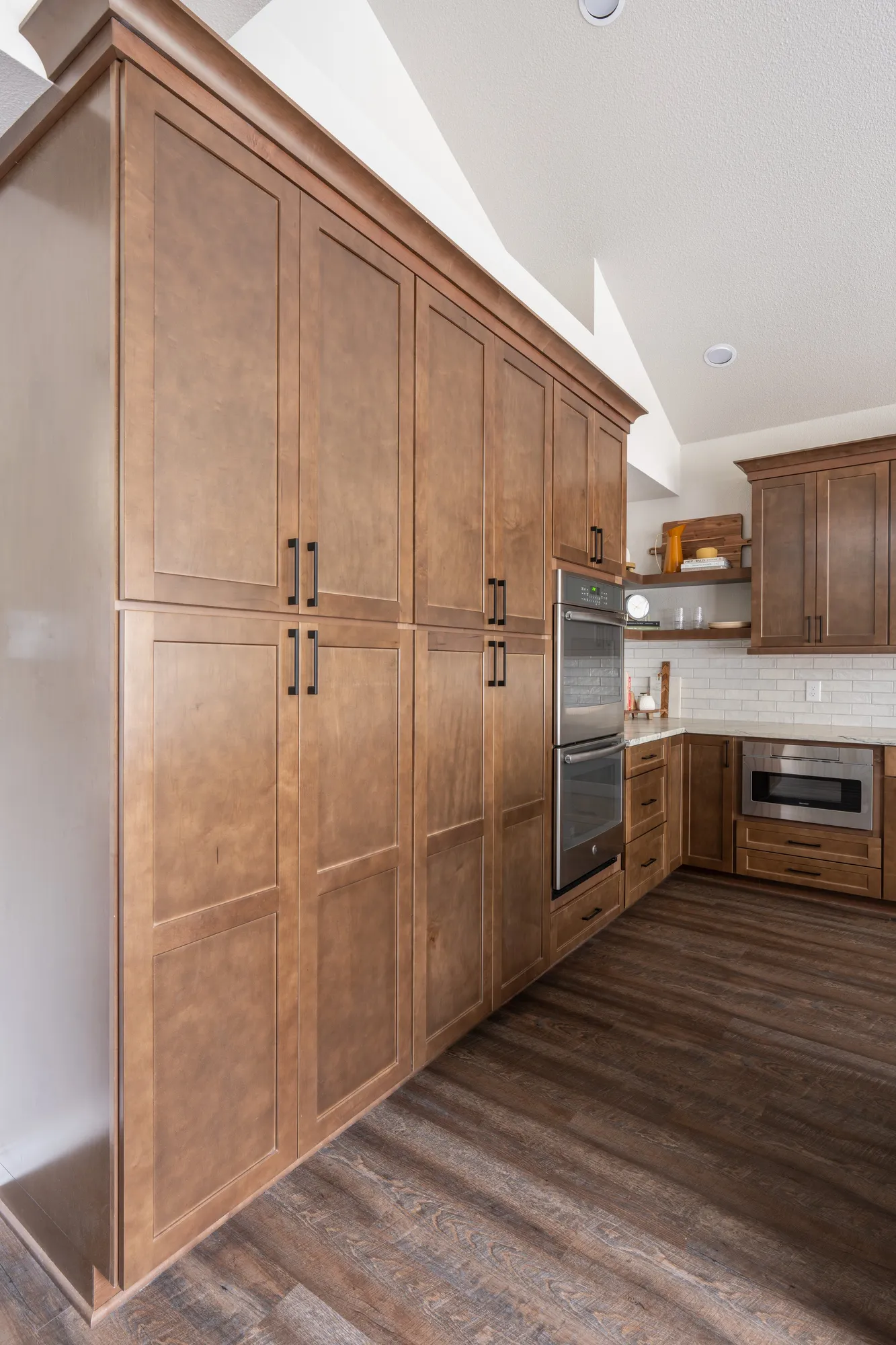 After: wall of tall wood pantry cabinets with built-in double ovens