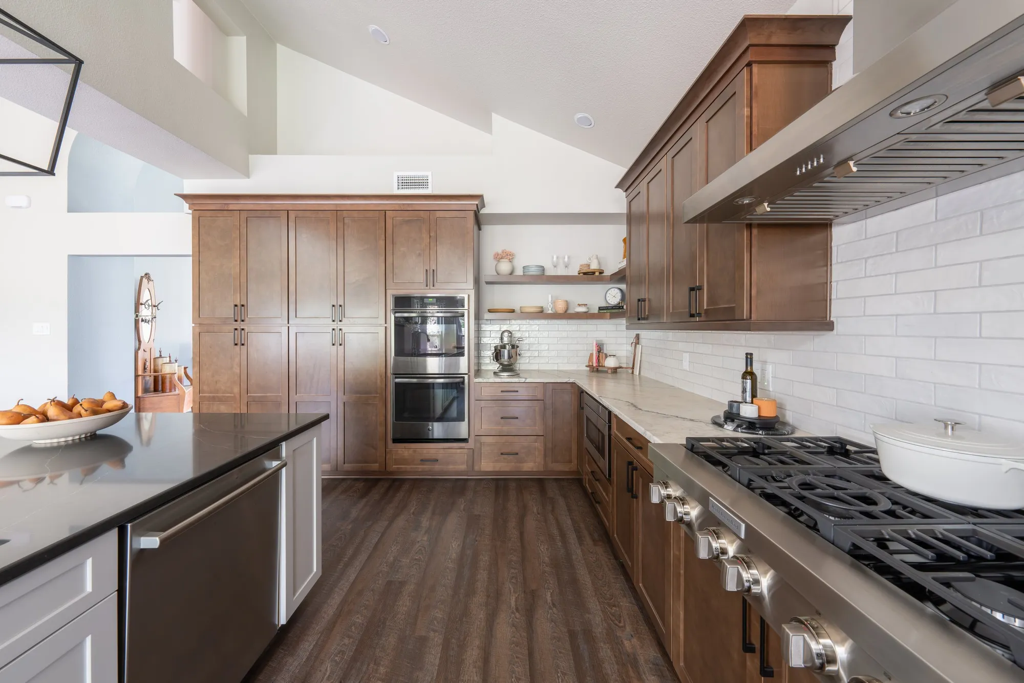 After: kitchen with a gas range, white subway tile, wood cabinets and double ovens