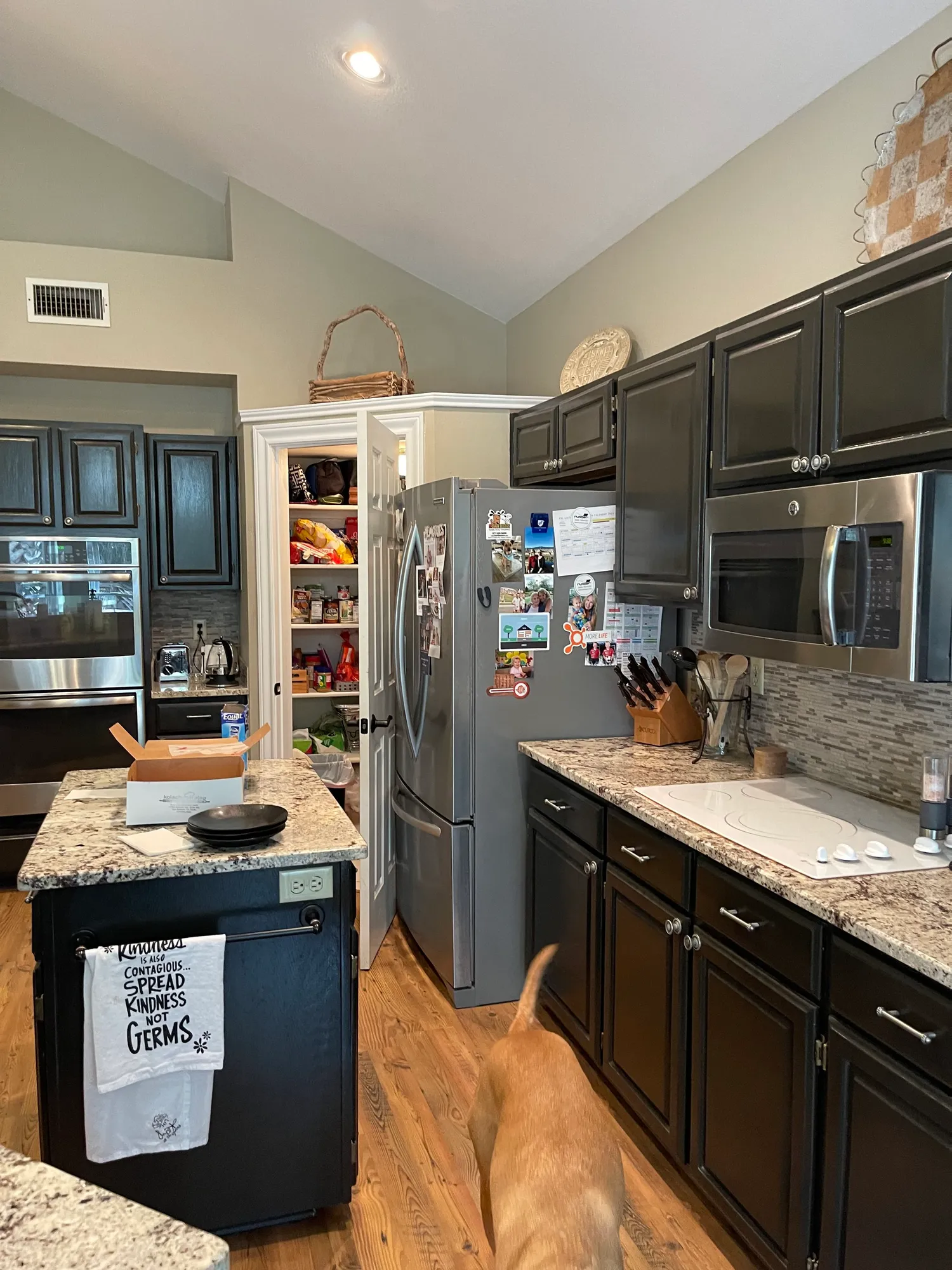 Before: dark kitchen cabinets with a granite counter and stainless refrigerator