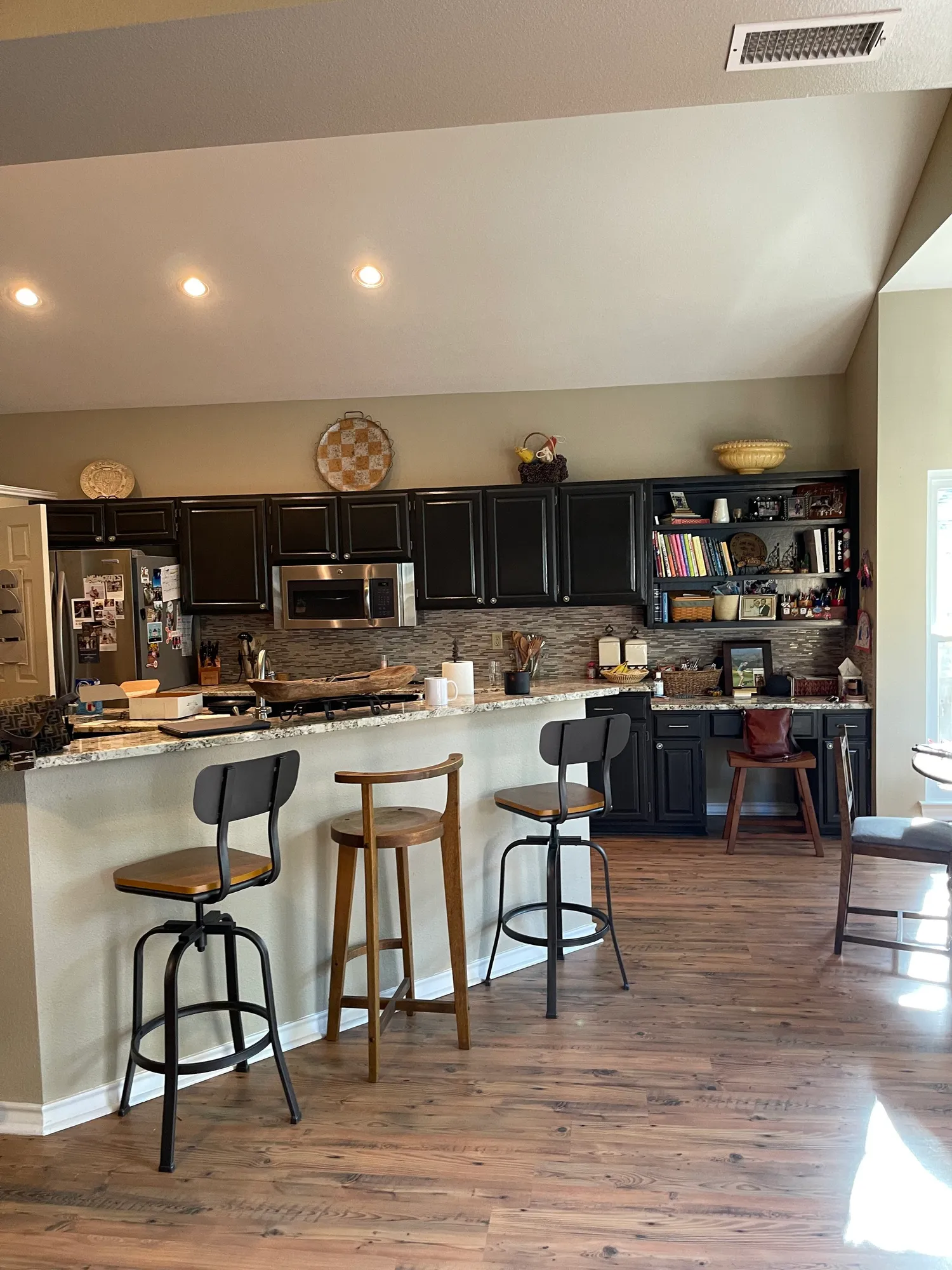 Before: kitchen with dark cabinets and a raised breakfast bar with stools