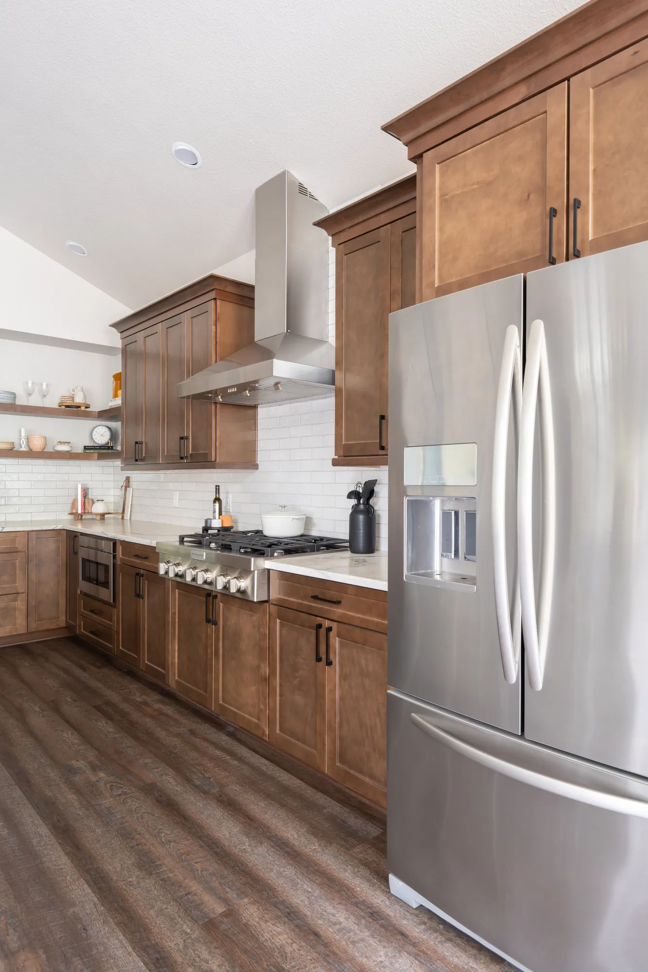After: stainless French-door refrigerator beside wood cabinets and a range hood