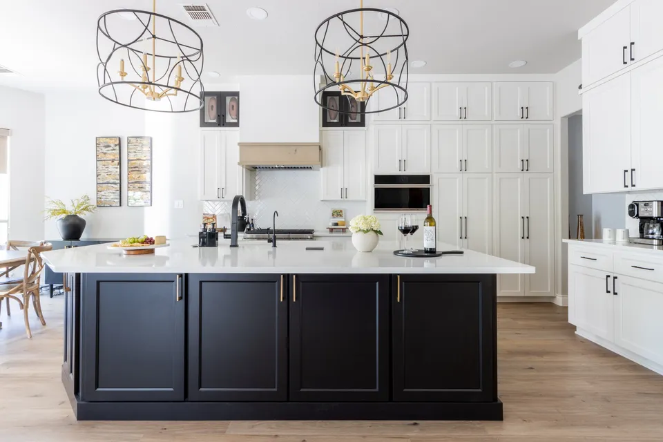 Kitchen with a dark island, white cabinetry and a dining area