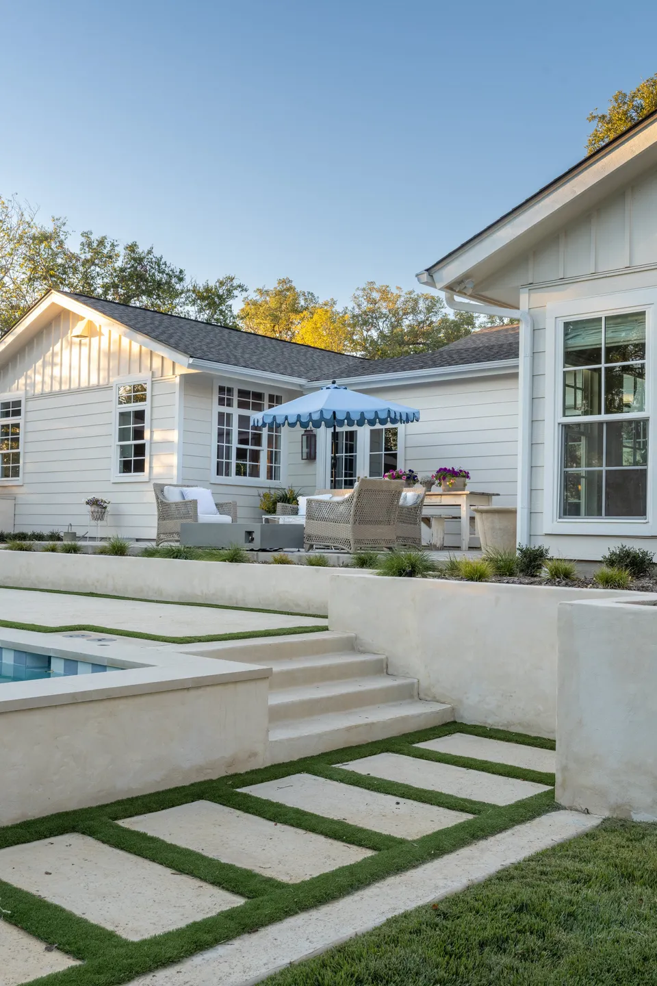 Courtyard patio with a pool, steps and a blue striped umbrella between the two additions