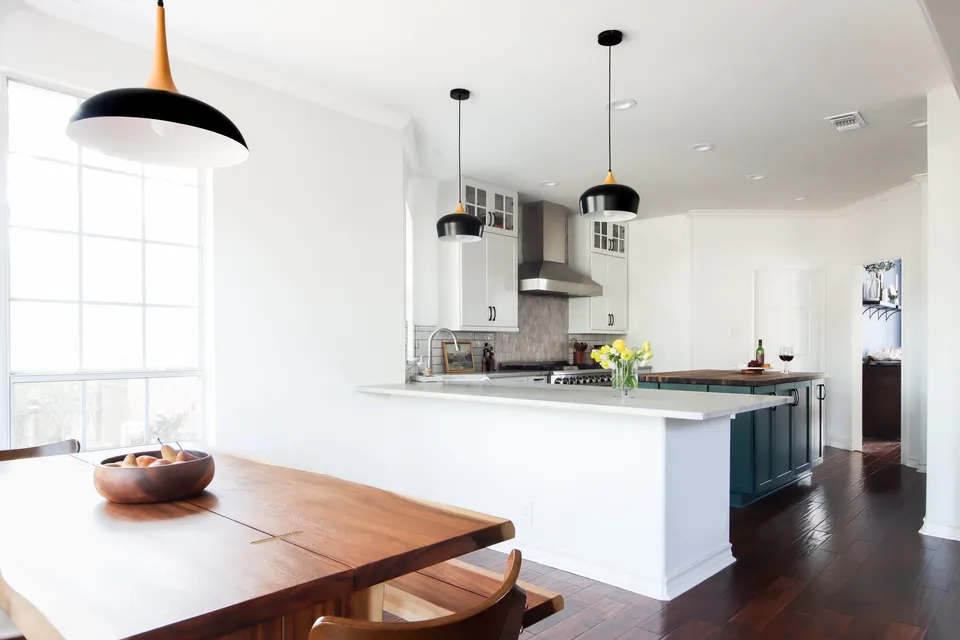 White kitchen with black pendant lights over a peninsula