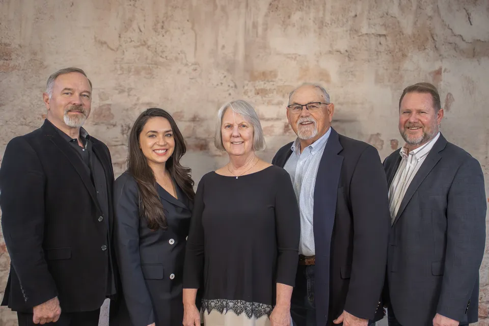 The KM BUILDERS executive team standing in front of a brick wall