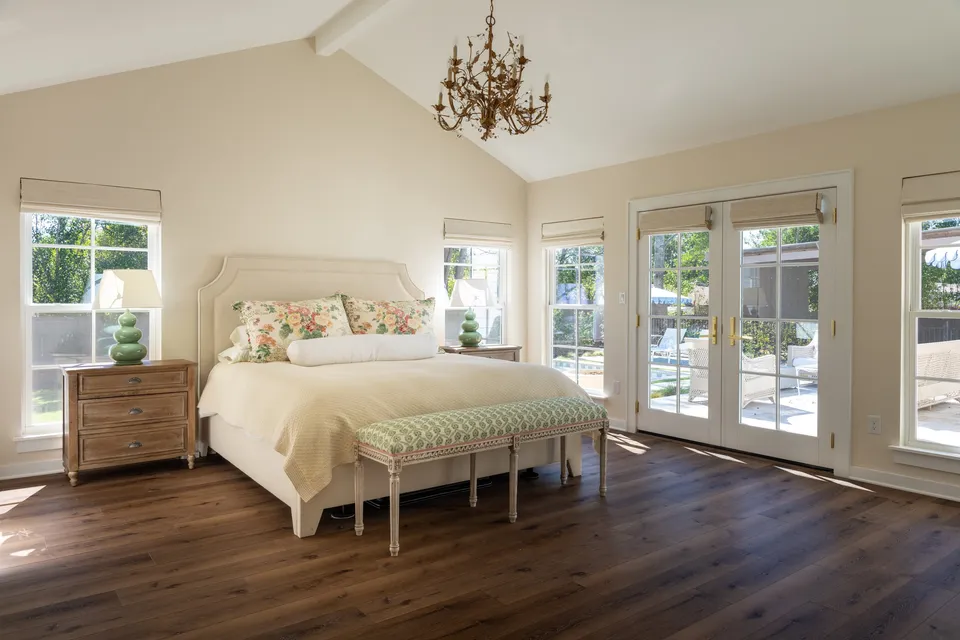 Primary bedroom with vaulted ceiling, chandelier and French doors to the patio