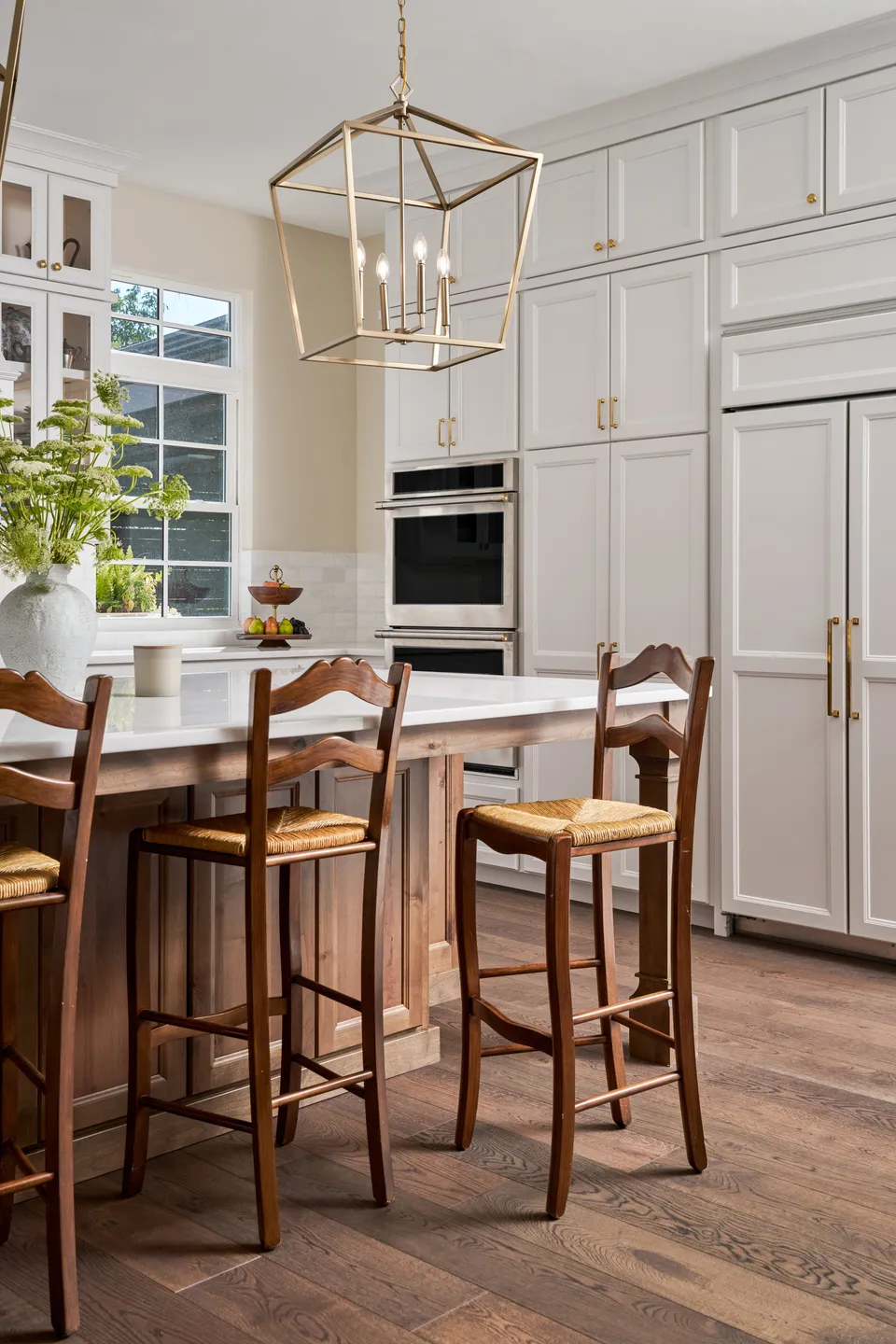 Kitchen island with rush-seat stools under a lantern pendant