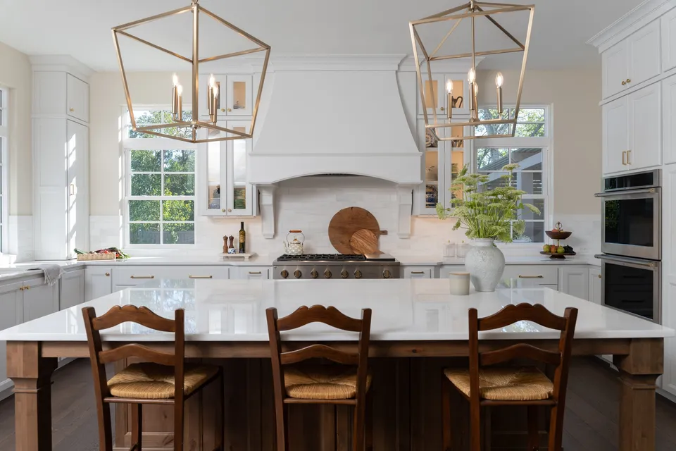 The finished kitchen with lantern pendants over a wood island and a range hood